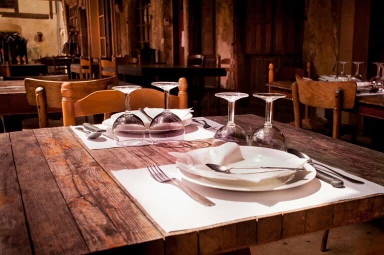 A rustic restaurant table set with wine glasses and cutlery invites guests to dine.