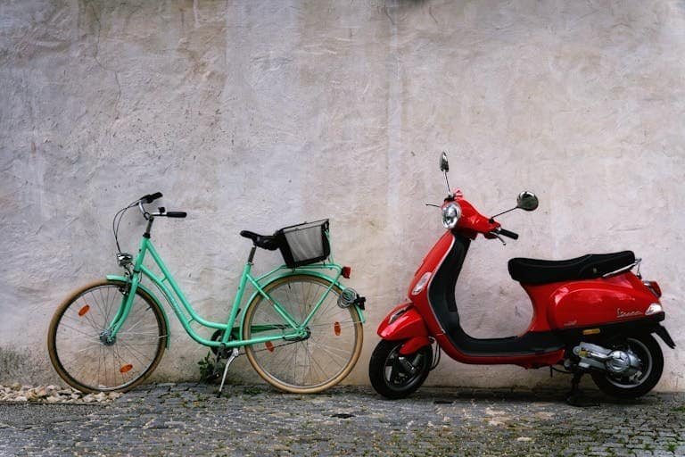 Parked bicycle and scooter side by side in front of a rustic wall, showcasing urban transportation options.