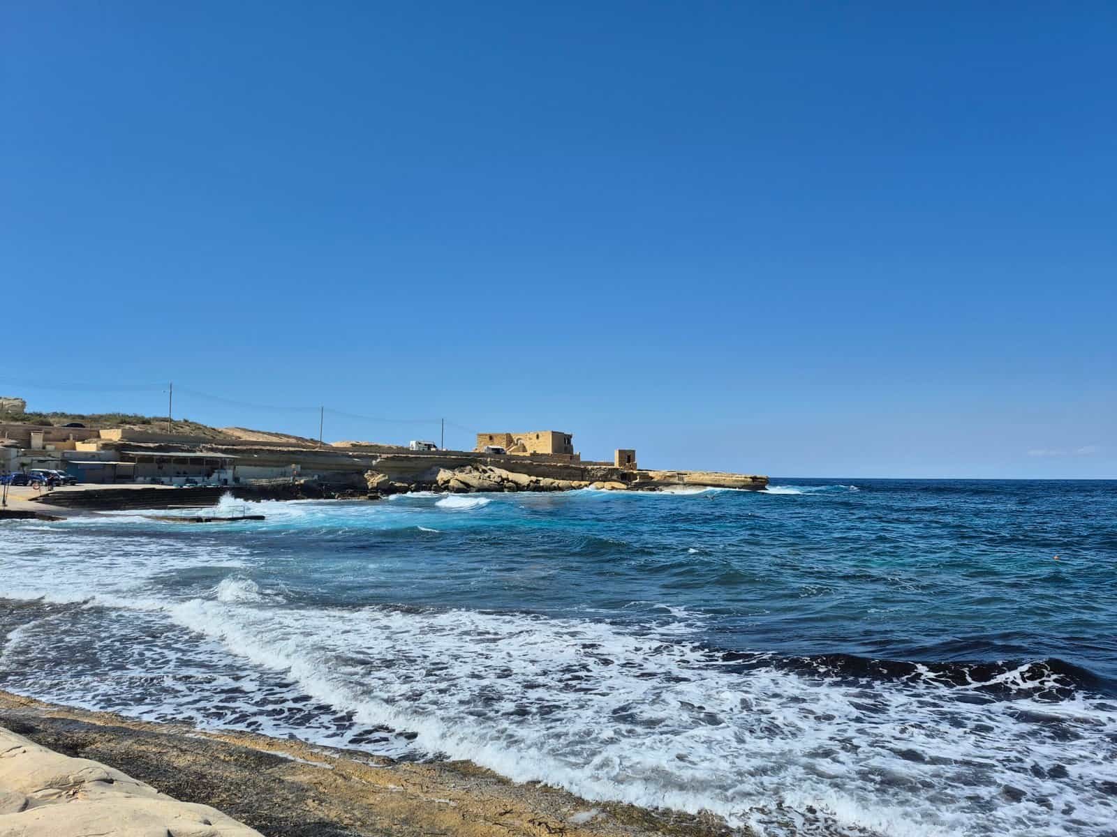 Coastal view with waves and buildings.