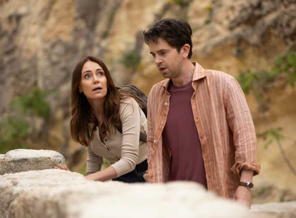 Keeley Hawes and Freddie Highmore as Julie and Edward peering over limestone rocks in The Assassin series 2
