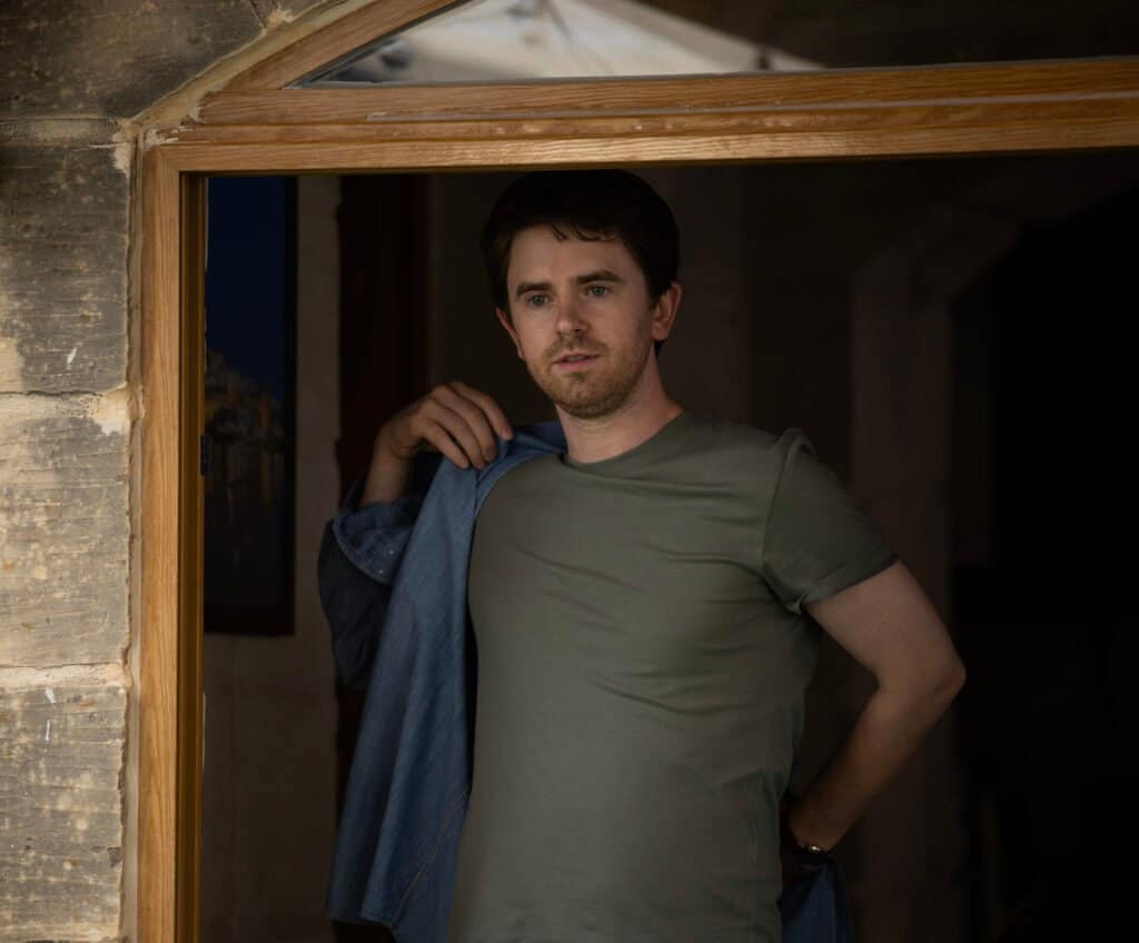 Freddie Highmore as Edward standing in a stone doorway in The Assassin series 2