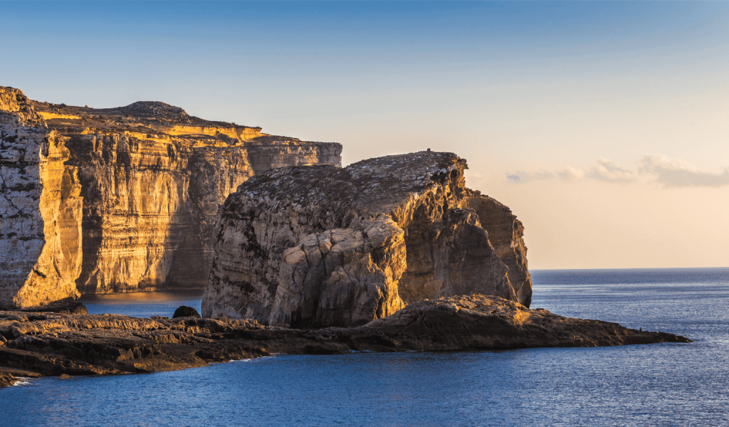 Fungus Rock, Dwerja Bay, Gozo. An islet set against sheer limestone cliffs.